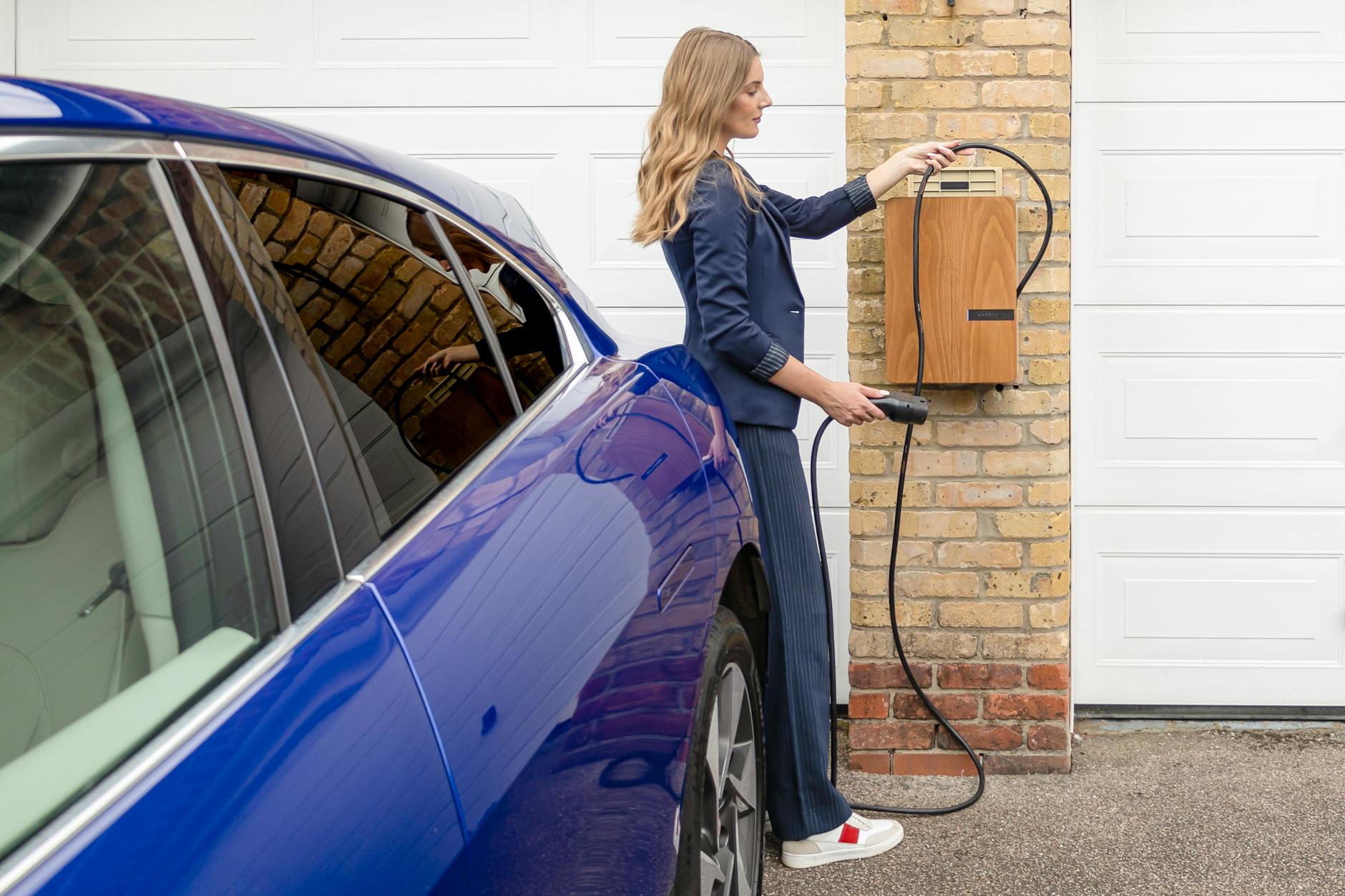 Femme branchant câble de recharge sur voiture électrique - borne IRVE
