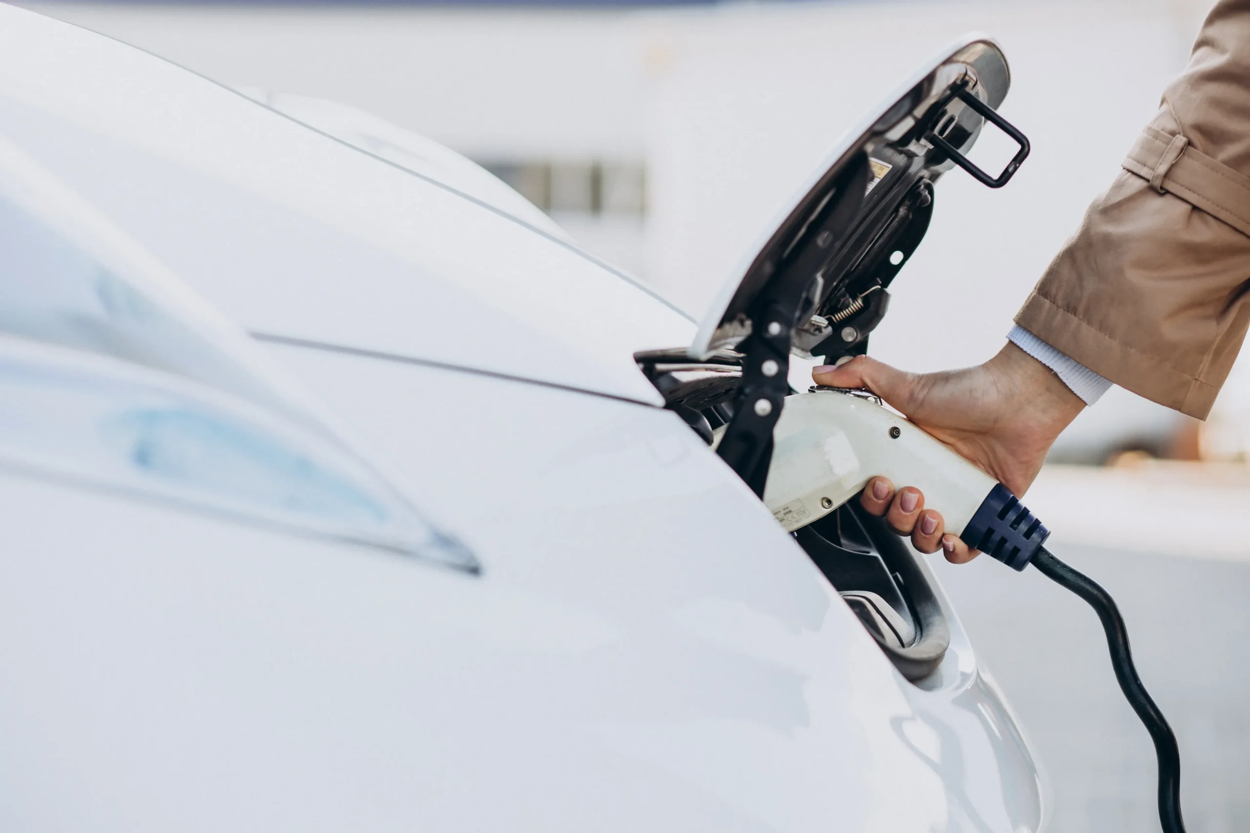 Femme branchant câble recharge véhicule électrique stationnement EHPAD résidence