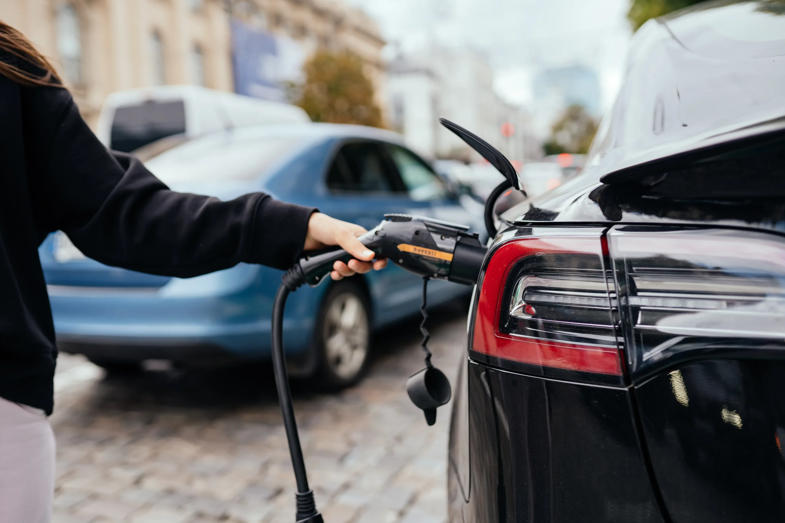 Femme près véhicule électrique chargé station recharge résidence services EHPAD