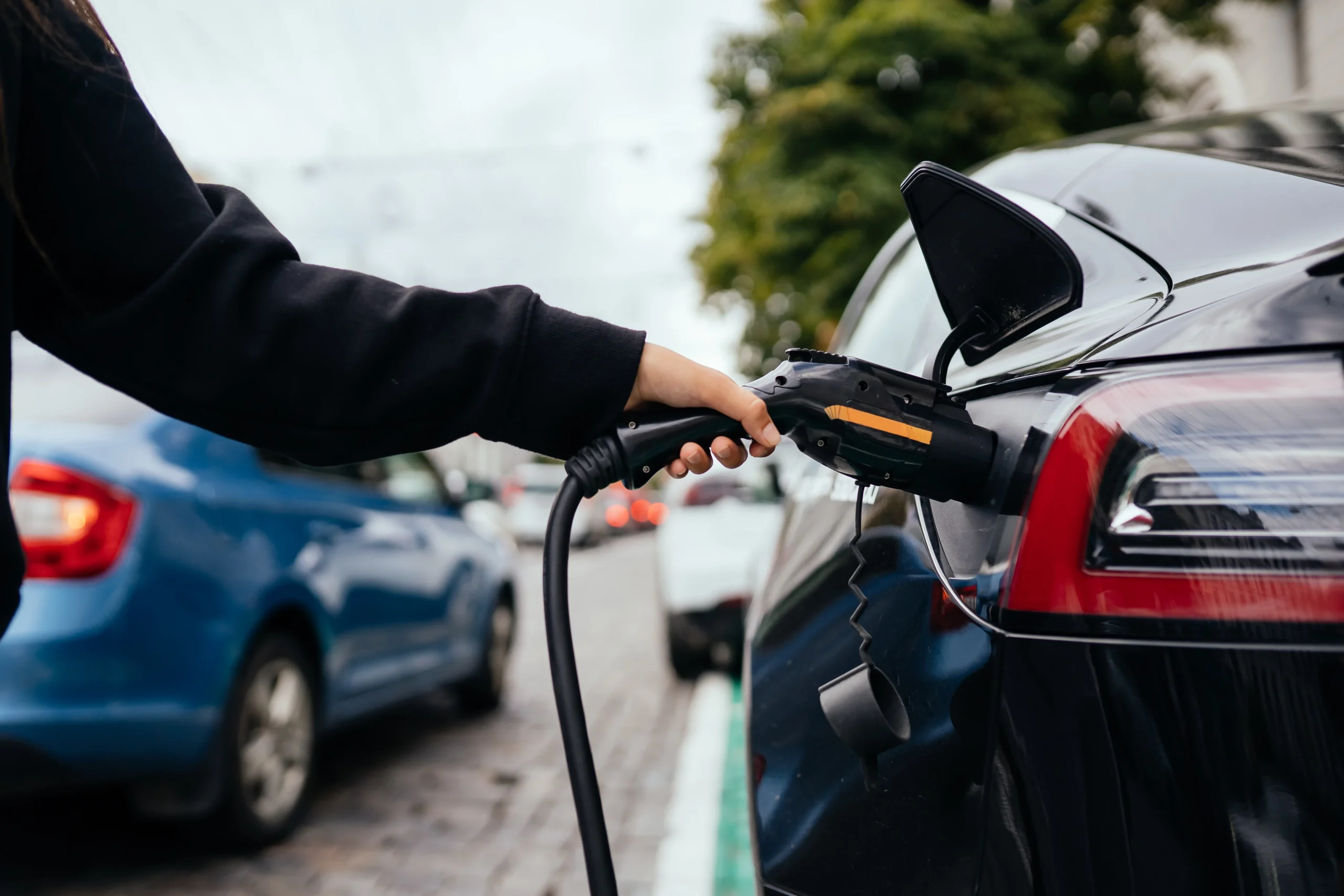 Femme près voiture électrique rechargée station recharge résidence services personnes âgées
